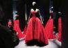 Schiaparelli at the V&A Is the Fashion Show You Walk Through Red strapless ballgown with a beaded bodice on a mannequin in a mirrored display.