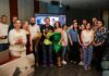 Oleksandr Tyshchenko’s “Somnia Disaster” Project Presented at Sofia University Group of people posing for a photo in a conference room, some holding bouquets, with a presentation screen in the background.