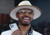 Who Is Stunt Lifestyle? Inside the We In Miami Podcast Host Turning Miami Into Viral Celebrity Media Man in a white suit and hat, smiling, holding a smartphone and a citrus cocktail.