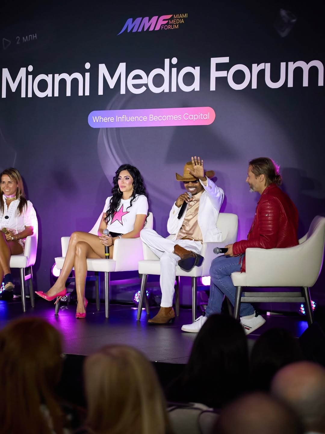 Panel of four speakers on stage at the Miami Media Forum, with a large 'Miami Media Forum' banner behind them and purple lighting.
